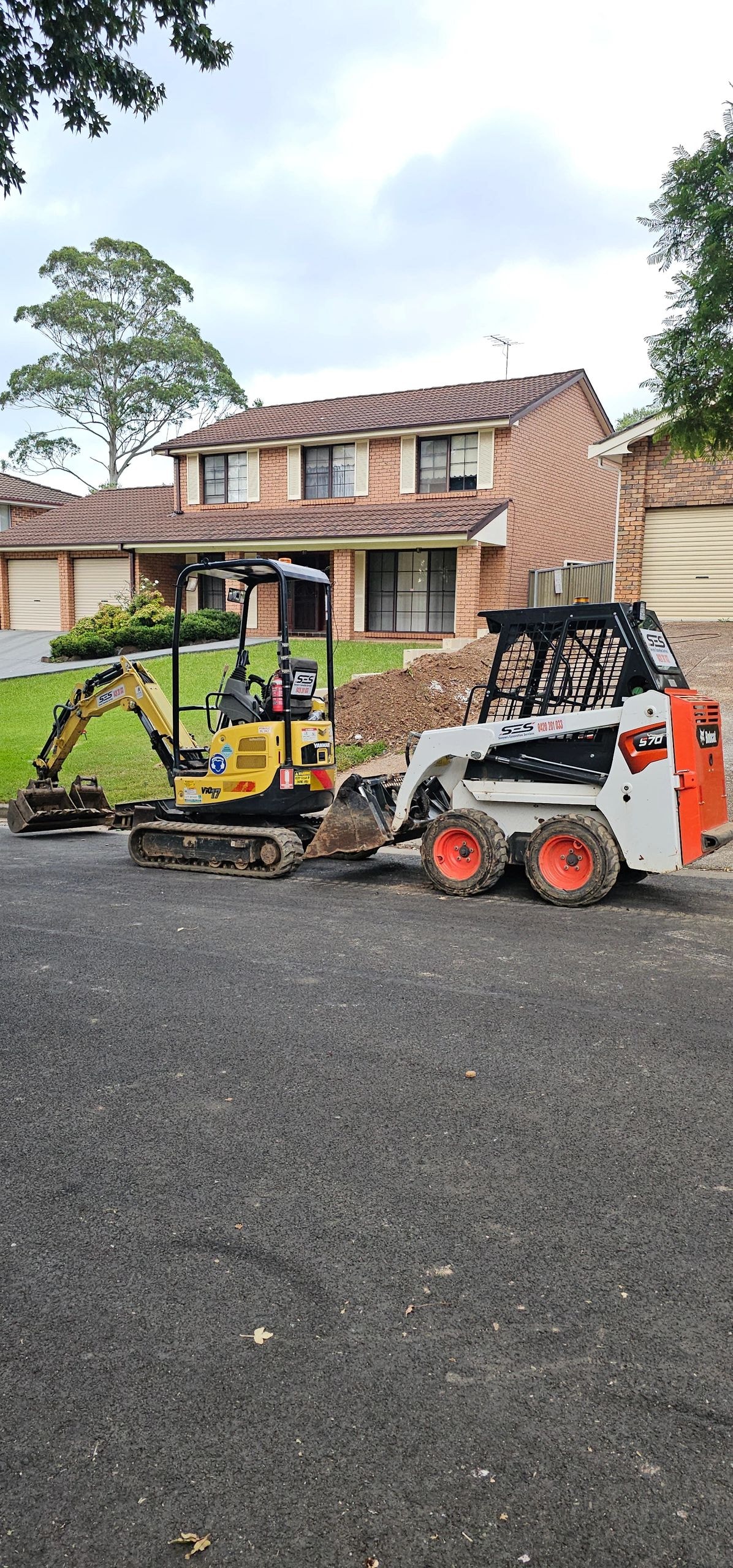 Excavator and bobcat at residential driveway