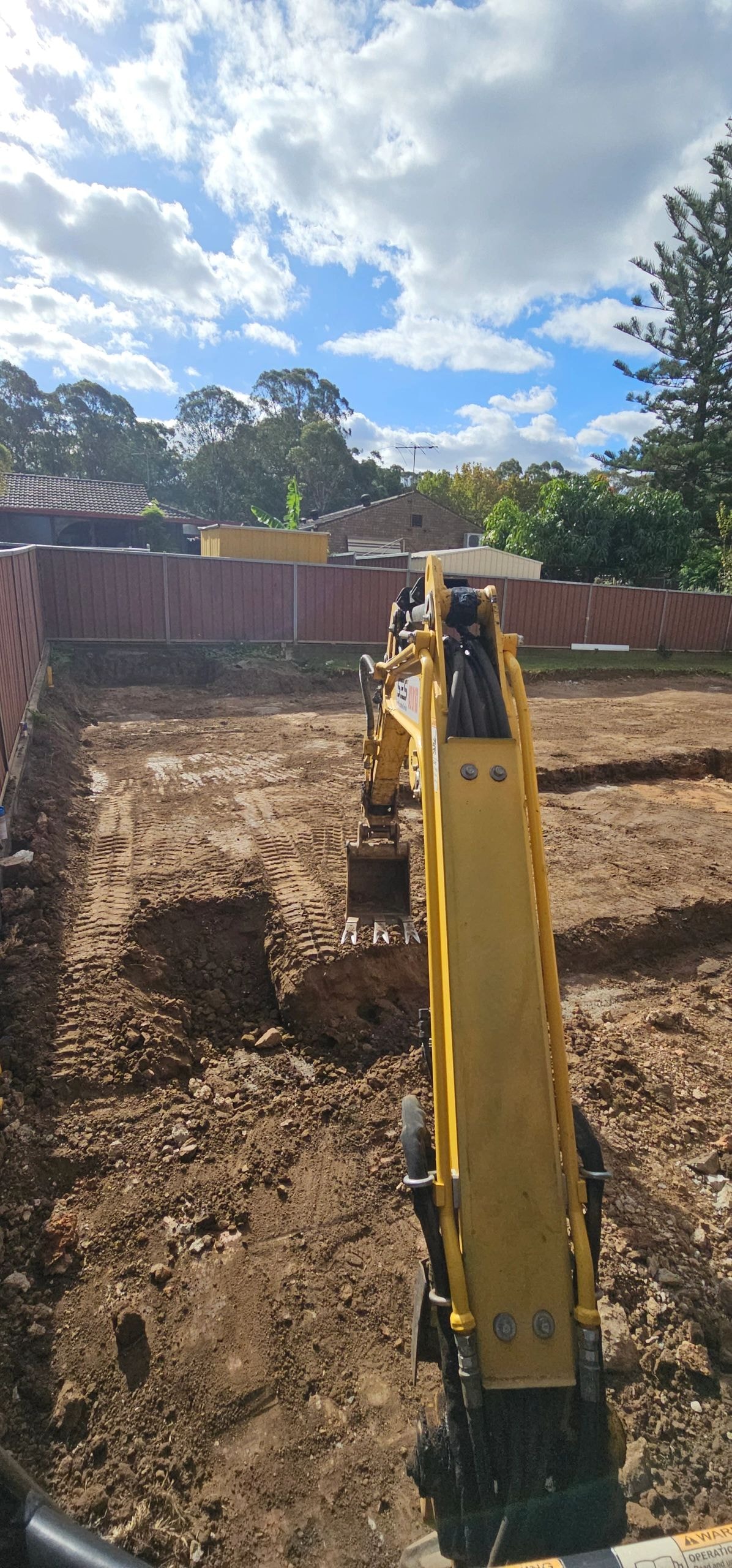 Yellow excavator digging on residential site