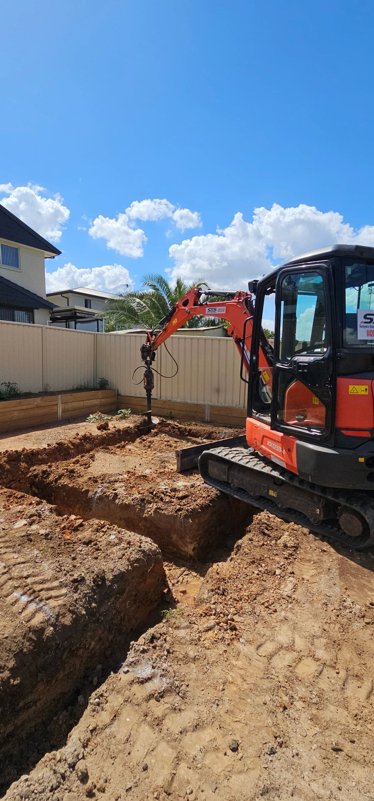 Excavator digging trench in residential backyard
